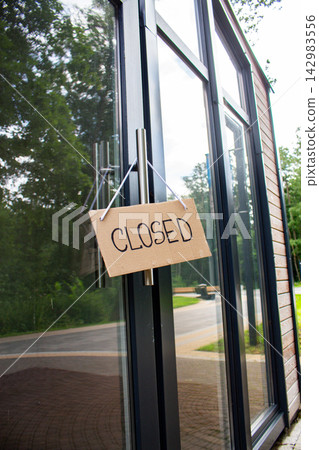CLOSED sign hanging on small shop door. Small business shutting down due to financial crisis. Local business unable to survive economic pressure CLOSED sign hanging on small shop door. Small business shutting down due to financial crisis. Local business unable to survive economic pressure 142983556