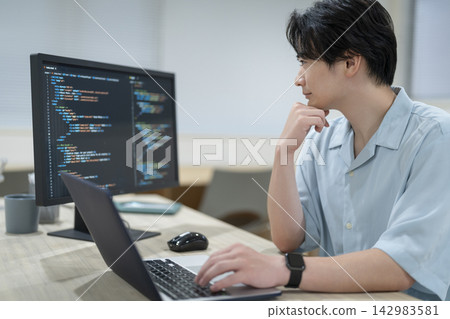A young engineer working on a computer - profile view A young engineer working on a computer - profile view 142983581