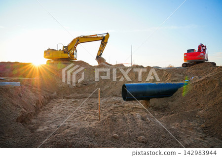 Excavator on sewage line repair. Sewer pipe laying. Excavator on earthworks on construction site Excavator on sewage line repair. Sewer pipe laying. Excavator on earthworks on construction site 142983944