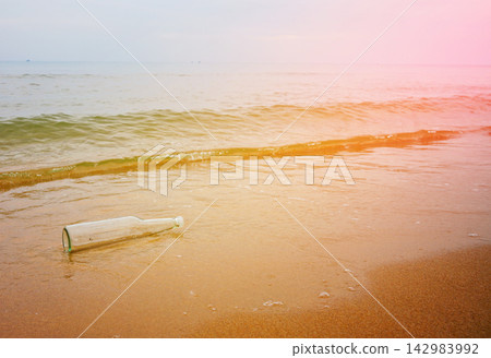 Message in bottle on sandy beach near ocean with gentle waves rolling Message in bottle on sandy beach near ocean with gentle waves rolling 142983992