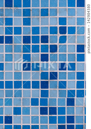 Blue and light blue square ceramic tiles forming an abstract grid pattern with white grout, creating a textured background or surface Blue and light blue square ceramic tiles forming an abstract grid pattern with white grout, creating a textured background or surface 142984380