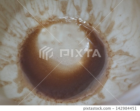 Coffee and foam remaining at the bottom of the empty cup. Coffee and foam remaining at the bottom of the empty cup. 142984451