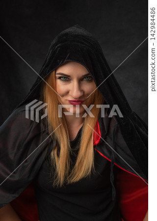 Mysterious woman wearing a black hood and cape with red lining, looking directly at the viewer with an intriguing expression, evoking concepts of fantasy, power, and secrets Mysterious woman wearing a black hood and cape with red lining, looking directly at the viewer with an intriguing expression, evoking concepts of fantasy, power, and secrets 142984486
