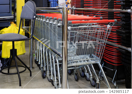 Row of Metal Shopping Carts with Red Handles and Stacked Baskets in Store Area Row of Metal Shopping Carts with Red Handles and Stacked Baskets in Store Area 142985117