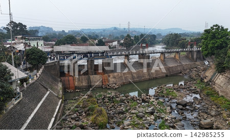 An aerial drone perspective reveals the historic Katulampa Dam spanning the Ciliwung River in Bogor at summer time An aerial drone perspective reveals the historic Katulampa Dam spanning the Ciliwung River in Bogor at summer time 142985255