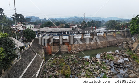 An aerial drone perspective reveals the historic Katulampa Dam spanning the Ciliwung River in Bogor at summer time An aerial drone perspective reveals the historic Katulampa Dam spanning the Ciliwung River in Bogor at summer time 142985256