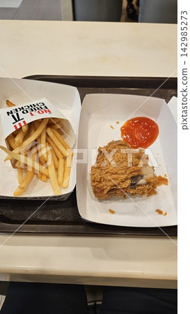 Golden French fries in branded paper pouch on tray close u 142985273