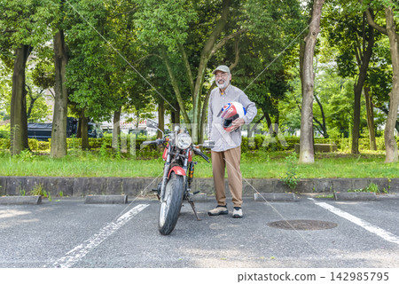 A smiling senior male rider and his 250cc motorcycle. 142985795