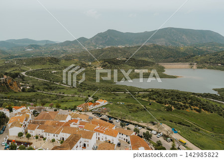 Elevated view of village rooftops overlooking a reservoir and green hills Elevated view of village rooftops overlooking a reservoir and green hills 142985822