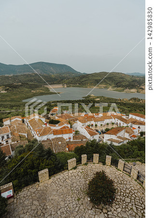 Elevated view of village rooftops overlooking a reservoir and green hills Elevated view of village rooftops overlooking a reservoir and green hills 142985830