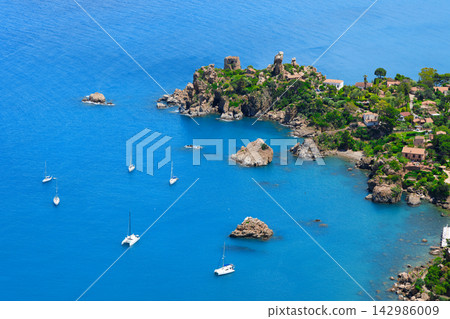Aerial view of a Mediterranean coastline with rocky cliffs and sailboats in a blue bay Aerial view of a Mediterranean coastline with rocky cliffs and sailboats in a blue bay 142986009