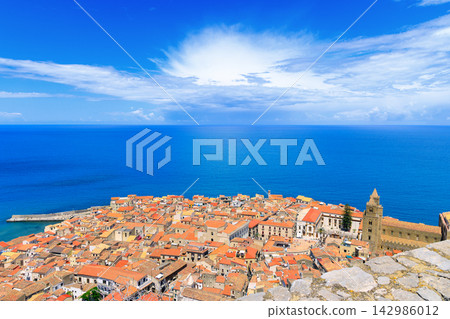 Aerial view of a historic coastal town in Sicily with prominent cathedral by the blue sea Aerial view of a historic coastal town in Sicily with prominent cathedral by the blue sea 142986012