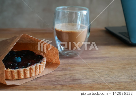 Blueberry muffin and cup of coffee with milk. Blueberry fruit on tart and coffee cup. Sweet breakfast. Cappuccino and dessert. Tart with berry jam and hot coffee. Homemade pastry. 142986132