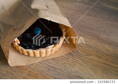 Blueberry muffin and cup of coffee with milk. Blueberry fruit on tart and coffee cup. Sweet breakfast. Cappuccino and dessert. Tart with berry jam and hot coffee.  142986133