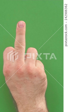 Abusive gesture fuck on chromakey. Male hand shows middle finger, offensive gesture isolated on green background. Fuck You concept. Close Up. Bad expression, provocation. Rude attitude. Fuck off sign 142986362