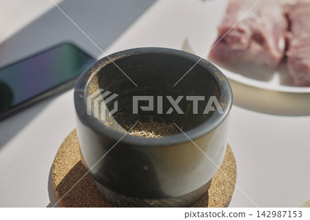 Whole cumin seeds placed in mortar beside raw pork. Concept of preparing spices Whole cumin seeds placed in mortar beside raw pork. Concept of preparing spices 142987153