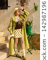 Trendy fashionista in lime raincoat and polka dot skirt on sunny urban day 142987196
