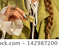Fashionable hand with creative manicure holding ceramic tag in sunlight 142987200