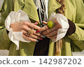 Fashionable woman's hands with statement rings and trendy nail art in green coat 142987202
