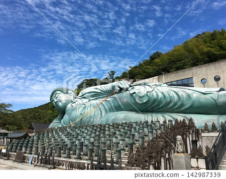 The reclining Buddha statue at Nanzoin Temple against the autumn sky. A popular tourist spot in Fukuoka. The reclining Buddha statue at Nanzoin Temple against the autumn sky. A popular tourist spot in Fukuoka. 142987339