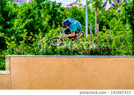 A young man practicing BMX and performing tricks at the skatepark A young man practicing BMX and performing tricks at the skatepark 142987433