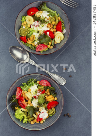 Fresh pasta and chickpea salad with leafy greens and tomatoes Fresh pasta and chickpea salad with leafy greens and tomatoes 142987483