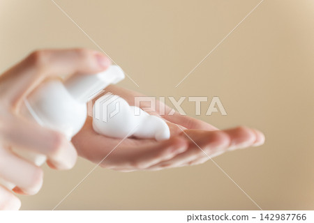 Extreme close up, palm of hands on isolated background, young woman applying hand foam soap or foam to wash face, skin care, cleansing, hygiene, health care. Finger presses taking foam from bottle Extreme close up, palm of hands on isolated background, young woman applying hand foam soap or foam to wash face, skin care, cleansing, hygiene, health care. Finger presses taking foam from bottle 142987766