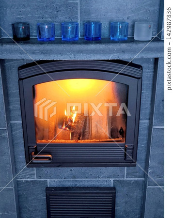 A cozy fireplace with a burning fire and candlesticks. A cozy fireplace with a burning fire and candlesticks. 142987836