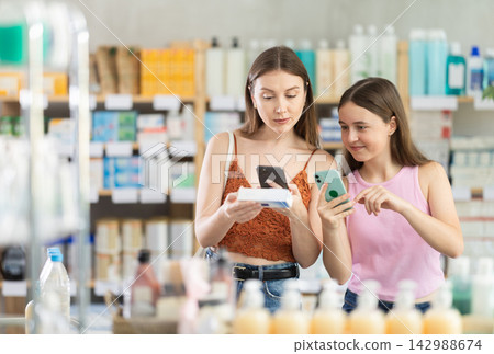 Woman and teen girl in pharmacy scans QR code pain relief ointment Woman and teen girl in pharmacy scans QR code pain relief ointment 142988674