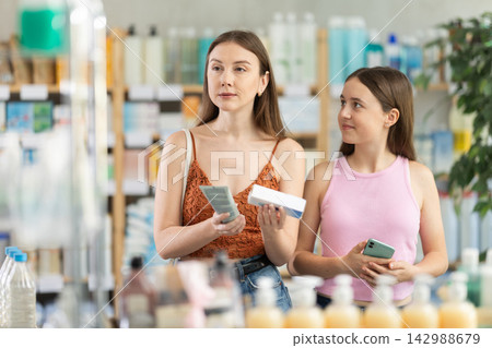 woman with a teenage daughter chooses an ointment in a package woman with a teenage daughter chooses an ointment in a package 142988679