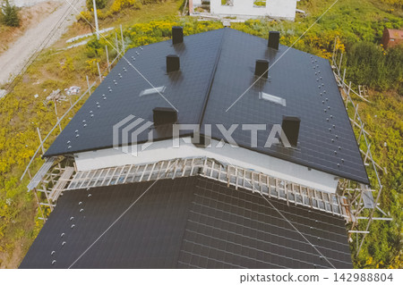 dark gray roof of an industrial building made of metal. Corrugated metal roof and metal roofing. Modern roof made of met dark gray roof of an industrial building made of metal. Corrugated metal roof and metal roofing. Modern roof made of met 142988804