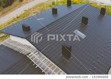 dark gray roof of an industrial building made of metal. Corrugated metal roof and metal roofing. Modern roof made of met dark gray roof of an industrial building made of metal. Corrugated metal roof and metal roofing. Modern roof made of met 142988806