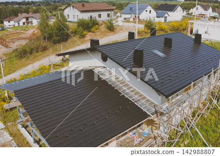 dark gray roof of an industrial building made of metal. Corrugated metal roof and metal roofing. Modern roof made of met dark gray roof of an industrial building made of metal. Corrugated metal roof and metal roofing. Modern roof made of met 142988807