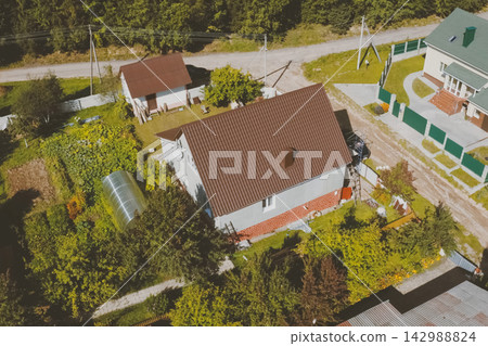 Brown metal tile on the roof of the house. Corrugated metal roof and metal roofing. Modern roof made of met Brown metal tile on the roof of the house. Corrugated metal roof and metal roofing. Modern roof made of met 142988824
