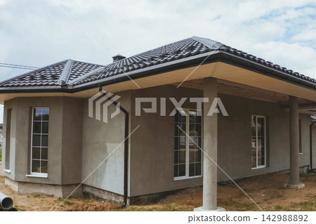 House with a brown metal roof.Corrugated metal roof and metal roofing. Modern roof made of metal. House with a brown metal roof.Corrugated metal roof and metal roofing. Modern roof made of metal. 142988892