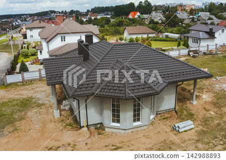 House with a brown metal roof.Corrugated metal roof and metal roofing. Modern roof made of metal. House with a brown metal roof.Corrugated metal roof and metal roofing. Modern roof made of metal. 142988893