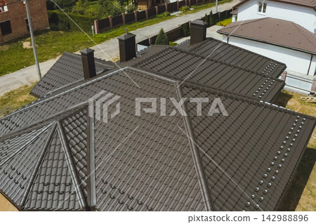 House with a brown metal roof.Corrugated metal roof and metal roofing. Modern roof made of metal. House with a brown metal roof.Corrugated metal roof and metal roofing. Modern roof made of metal. 142988896