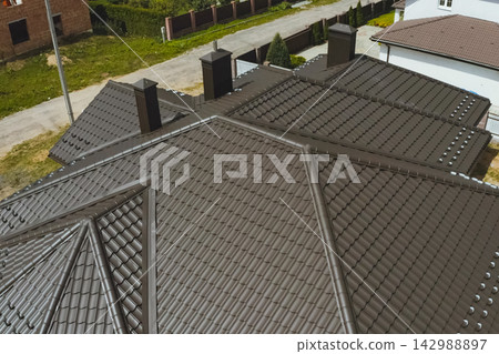 House with a brown metal roof.Corrugated metal roof and metal roofing. Modern roof made of metal. House with a brown metal roof.Corrugated metal roof and metal roofing. Modern roof made of metal. 142988897