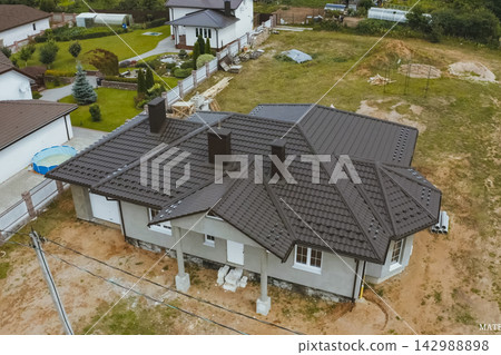 House with a brown metal roof.Corrugated metal roof and metal roofing. Modern roof made of metal. House with a brown metal roof.Corrugated metal roof and metal roofing. Modern roof made of metal. 142988898