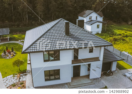 House with a gray metal roof. Corrugated metal roof and metal roofing. Modern roof made of metal. 142988902