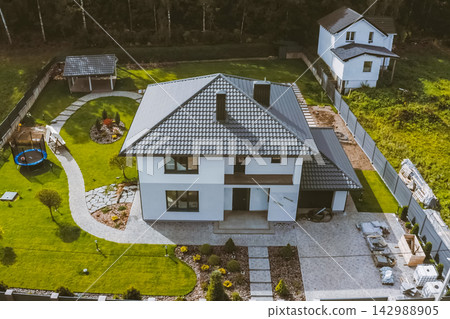 House with a gray metal roof. Corrugated metal roof and metal roofing. Modern roof made of metal. 142988905
