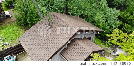 Bituminous tile for a roof. a roof from a bituminous tile. Modern roof made of met Bituminous tile for a roof. a roof from a bituminous tile. Modern roof made of met 142988950