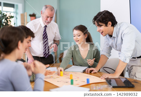 Teacher helping students play a game at the table Teacher helping students play a game at the table 142989032