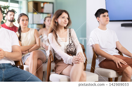 European woman is sitting among a group of people in an audience and listening to a lecture on finance European woman is sitting among a group of people in an audience and listening to a lecture on finance 142989033