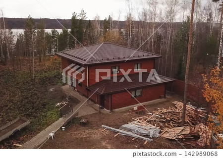 House with a brown metal roof.Corrugated metal roof and metal roofing. Modern roof made of metal. House with a brown metal roof.Corrugated metal roof and metal roofing. Modern roof made of metal. 142989068
