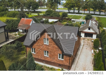 House with a brown metal roof.Corrugated metal roof and metal roofing. Modern roof made of metal. 142989111