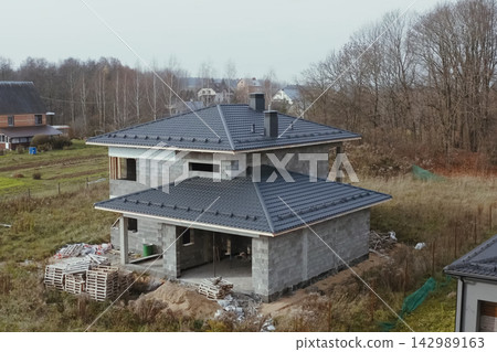 New houses under construction in the village. Houses with a roof made of metal. Corrugated metal roof and metal roofing. Modern roof made of metal. 142989163