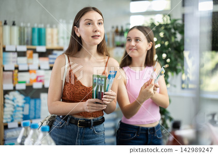 Woman with girl child buyer select toothbrush set Woman with girl child buyer select toothbrush set 142989247