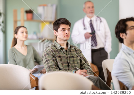 Young guy watching presentation with a doctor standing in background Young guy watching presentation with a doctor standing in background 142989290