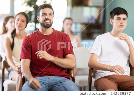 man sitting at a lecture on finance, he listens attentively and smiles man sitting at a lecture on finance, he listens attentively and smiles 142989377